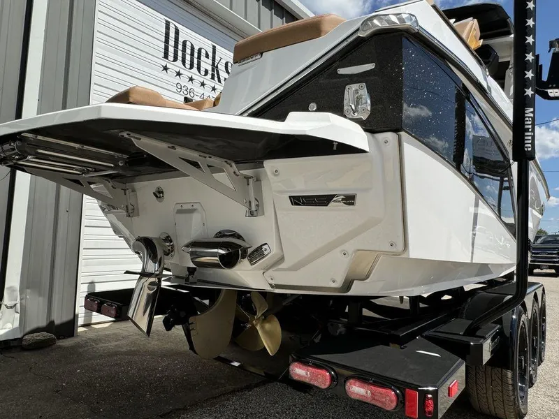 Slide: The Image of 2025 Nautique PARAGON 23 boat on trailer, rear view, white exterior, dockside location. - 11