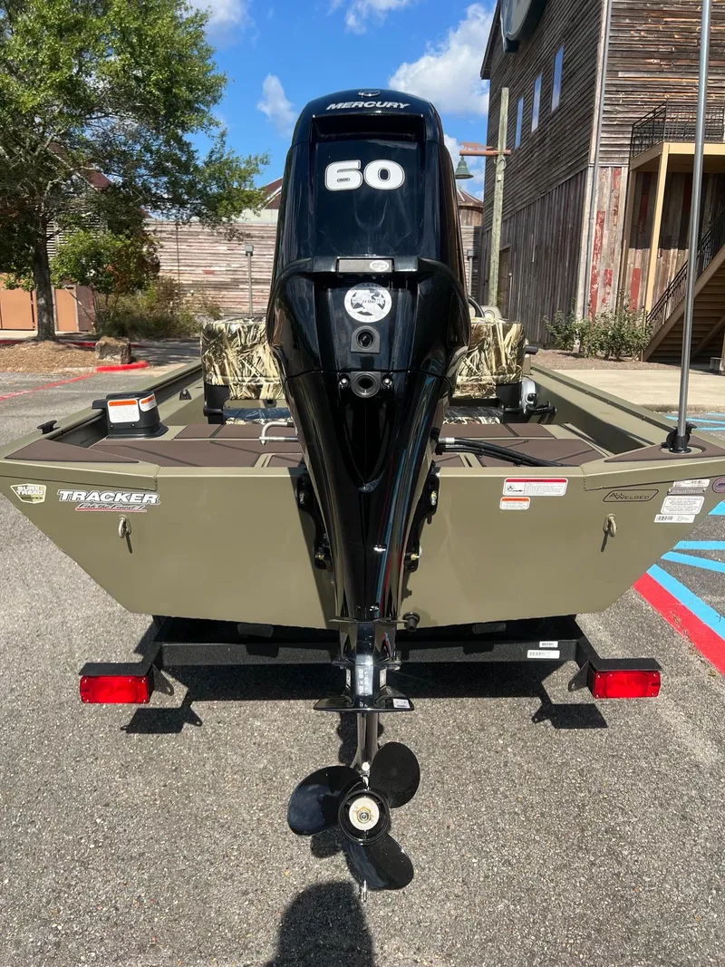 Slide: The Image of 2025 Tracker Grizzly 1754 SC boat with 60 HP engine, parked outdoors. - 6