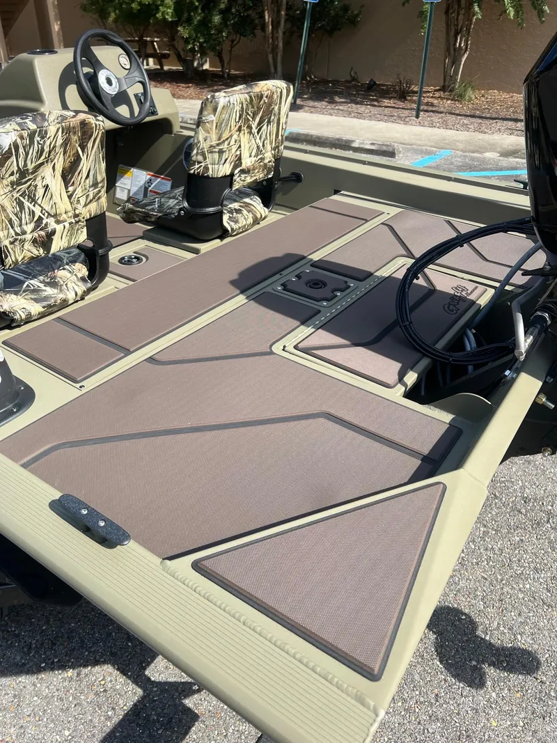 Slide: The Image of 2025 Tracker Grizzly 1754 SC boat interior with camo seats and spacious deck. - 8
