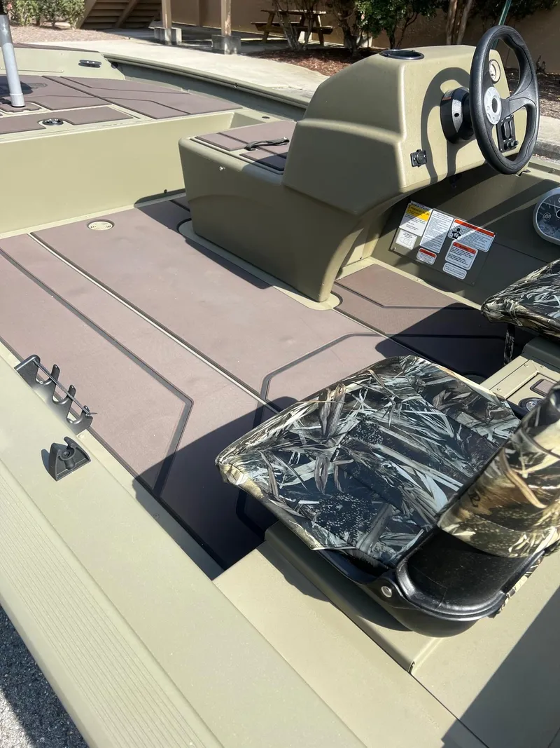 Slide: The Image of 2025 Tracker Grizzly 1754 SC boat interior with steering console and camo seats. - 9