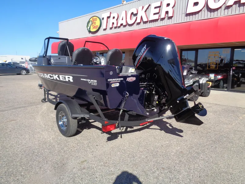 Slide: The Image of 2025 Tracker Pro Guide V-16 WT boat displayed outside dealership. - 2