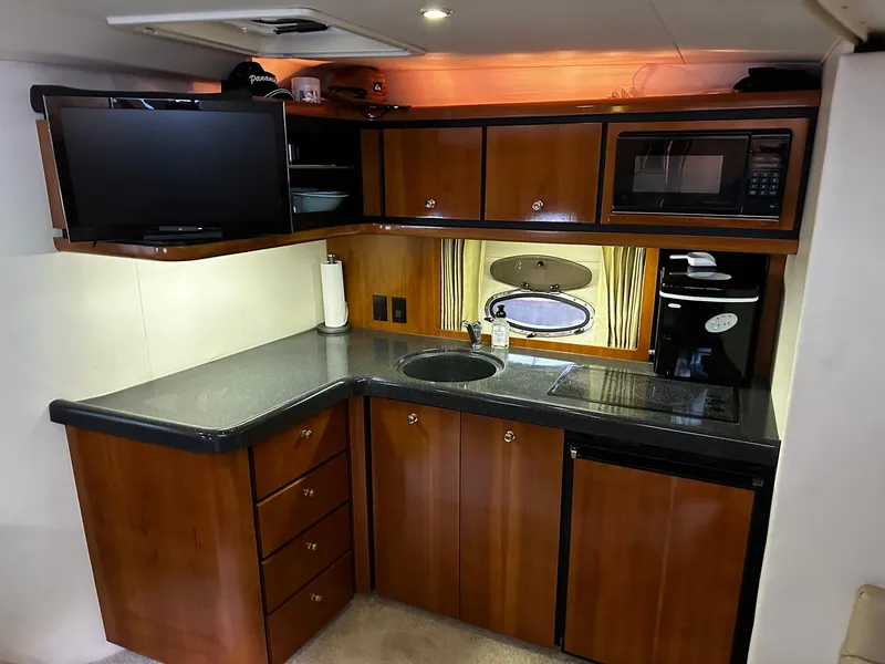 Slide: The Image of Interior of 2000 Carver 400 Express Yacht kitchen with wood cabinets and modern appliances. - 16