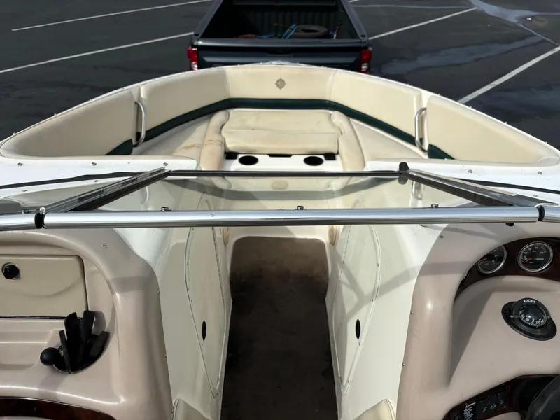 Slide: The Image of 2002 Bryant 214 boat interior with seating and dashboard in a parking lot. - 3