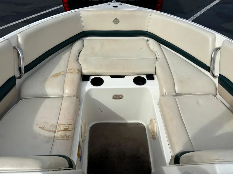 Slide: The Image of 2002 Bryant 214 boat interior with white and green seating, cup holders, and storage space. - 4