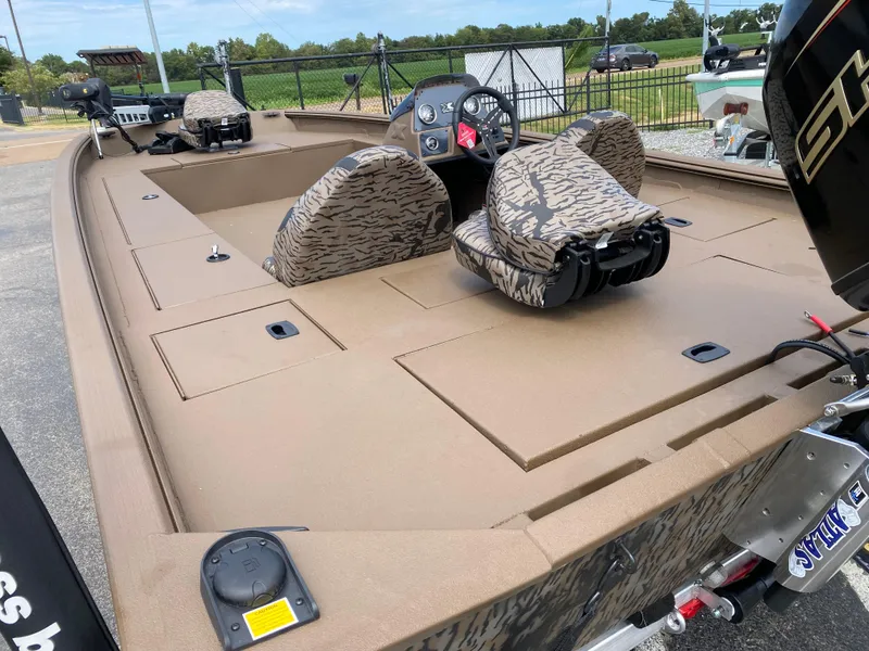 Slide: The Image of 2025 Xpress XP200 boat with camouflage seats and spacious deck, parked outdoors. - 11
