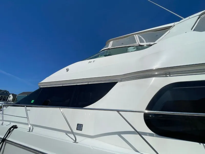 Slide: The Image of 2006 Carver 56 Voyager yacht with sleek white exterior under clear blue sky. - 8