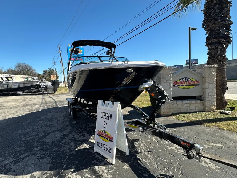 Slide: The Image of 2025 Regal LS4 Surf boat on trailer, displayed outdoors with dealership sign. - 1