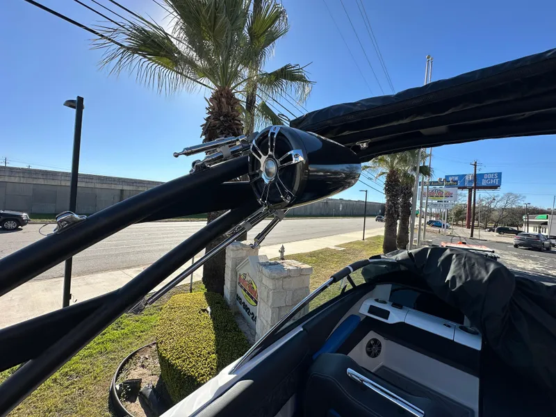 Slide: The Image of 2025 Regal LS4 Surf boat with sleek design, parked near palm trees. - 18