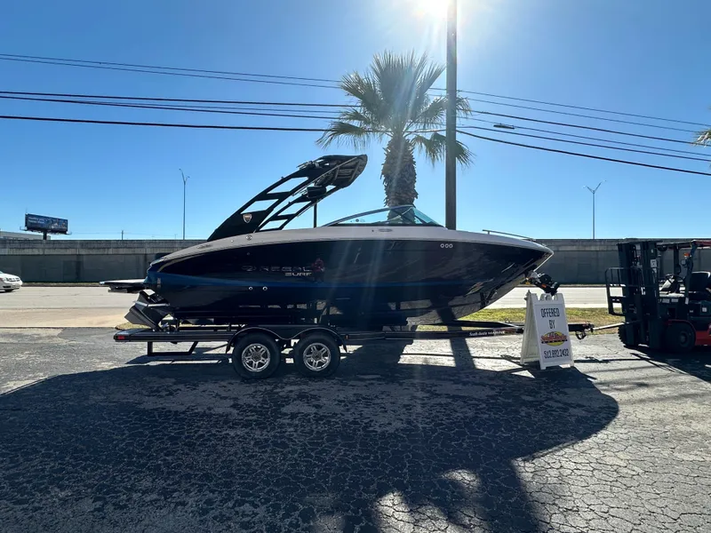 Slide: The Image of 2025 Regal LS4 Surf boat on trailer, parked under clear blue sky. - 2