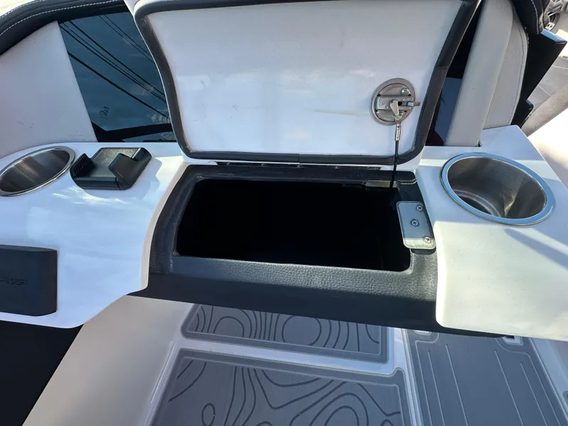 Slide: The Image of 2025 Regal LS4 Surf boat storage compartment with cup holders and open lid. - 46