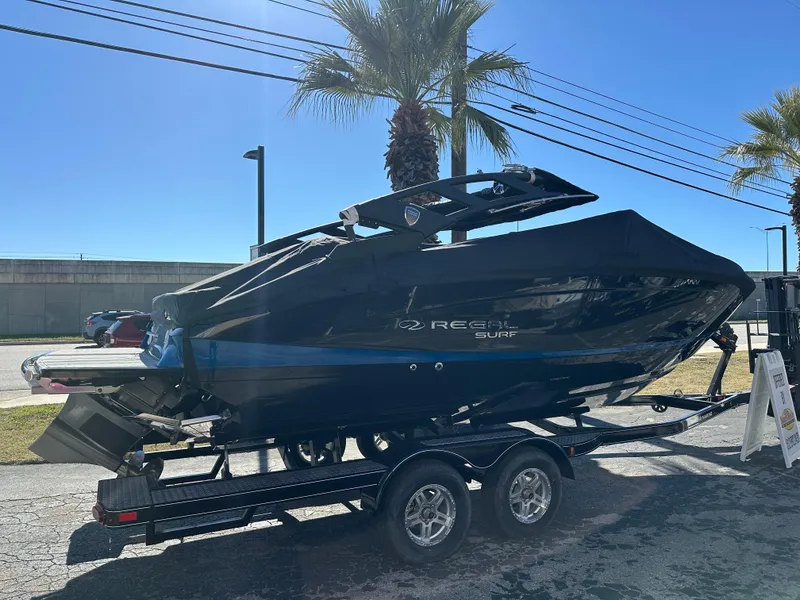 Slide: The Image of 2025 Regal LS4 Surf boat on trailer, sleek black design, parked outdoors. - 5