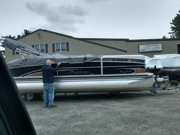 Slide: The Image of Man inspecting 2012 Premier Solaris pontoon boat outside a building. - 4