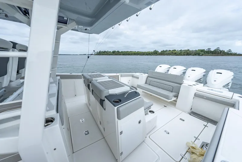 Slide: The Image of 2023 Pursuit S 428 Sport boat interior with seating and multiple engines on a calm water backdrop. - 25