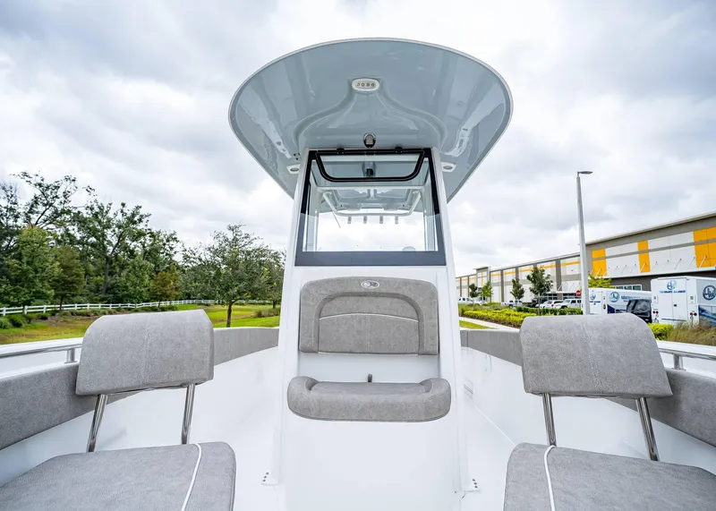 Slide: The Image of 2025 Sea Hunt Ultra 239 SE boat interior with seating and console, under cloudy sky. - 18