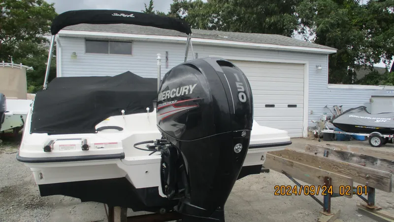 Slide: The Image of 2016 Sea Ray 21SPX-OB boat with Mercury 150 outboard motor, parked near a garage. - 2