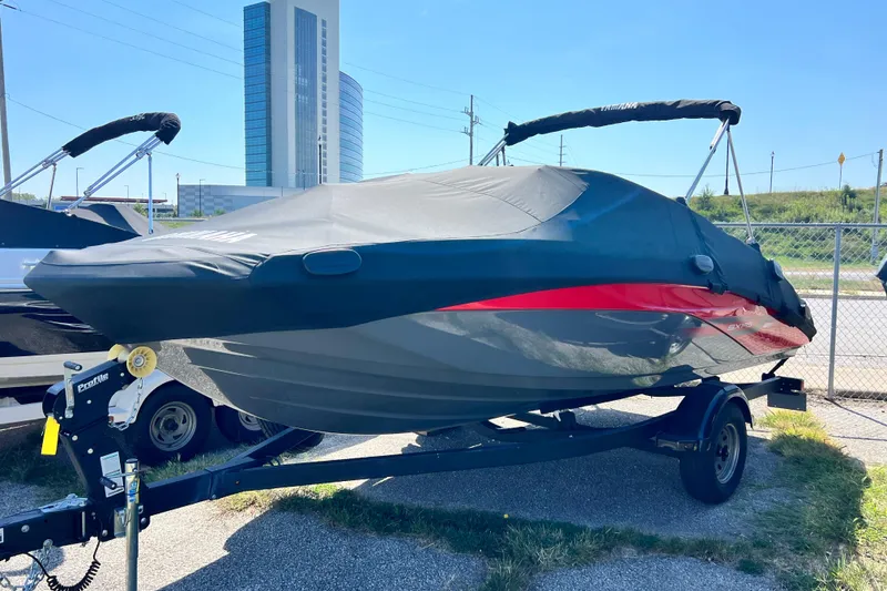 Slide: The Image of 2021 Yamaha Boats SX195 covered on trailer, parked outdoors near tall building. - 20