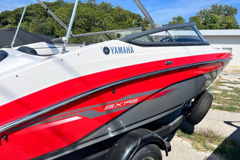 Slide: The Image of 2021 Yamaha Boats SX195 in red and white, parked on a trailer outdoors. - 6