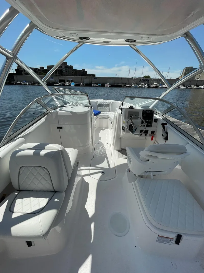 Slide: The Image of 2024 Sea Fox 228 Traveler boat interior with white seating and helm, docked at marina. - 11