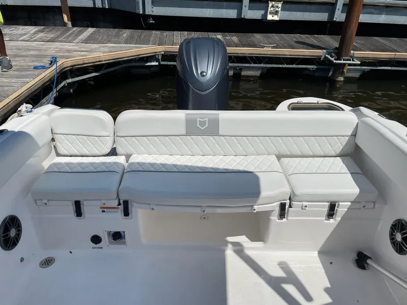 Slide: The Image of 2024 Sea Fox 228 Traveler boat interior with cushioned seating and motor at dock. - 7