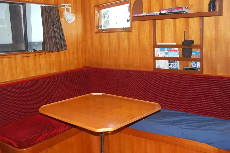 Slide: The Image of Cozy dining area in 1985 Sundowner Tug Princess Louisa with wooden table and red seating. - 13