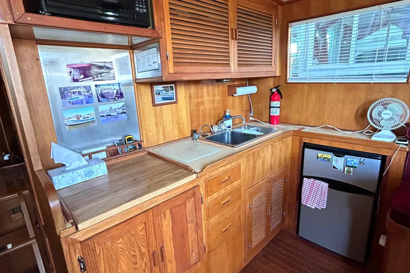 Slide: The Image of Compact wooden kitchen in 1985 Sundowner Tug Princess Louisa with sink, fridge, and microwave. - 15