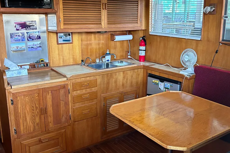 Slide: The Image of 1985 Sundowner Tug Princess Louisa interior with wooden cabinetry, kitchenette, and dining area. - 16