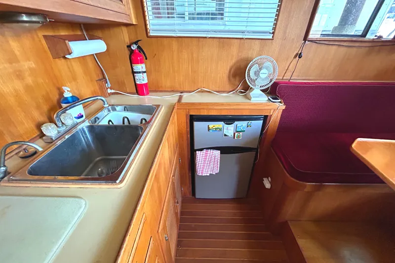 Slide: The Image of 1985 Sundowner Tug Princess Louisa kitchen with sink, mini fridge, and seating area. - 18