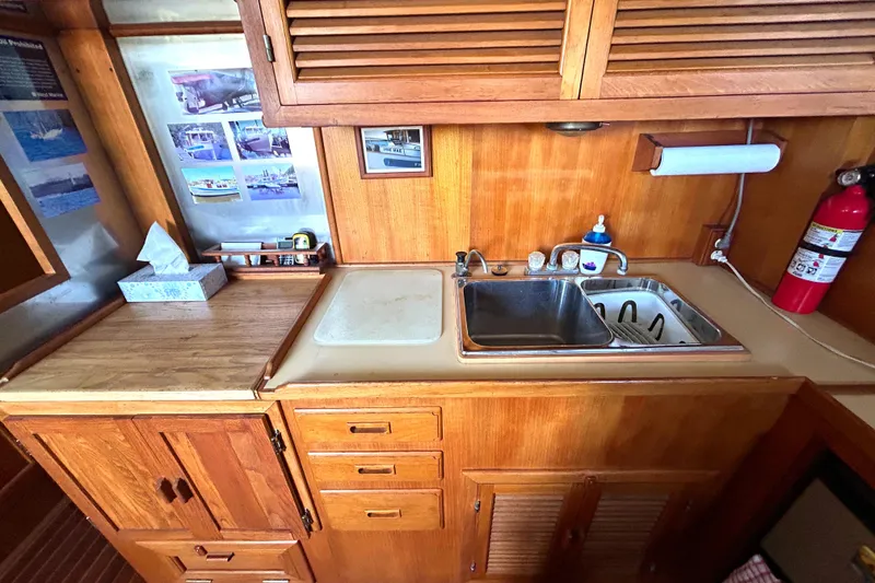 Slide: The Image of 1985 Sundowner Tug Princess Louisa kitchen with wooden cabinets, sink, and fire extinguisher. - 3