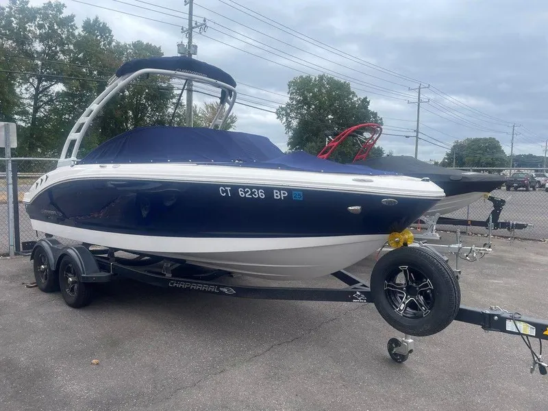 Slide: The Image of 2023 Chaparral 21 SSi boat on trailer, blue and white, parked outdoors. - 2