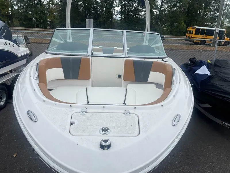 Slide: The Image of 2023 Chaparral 21 SSi boat with white and tan seating, parked outdoors. - 3