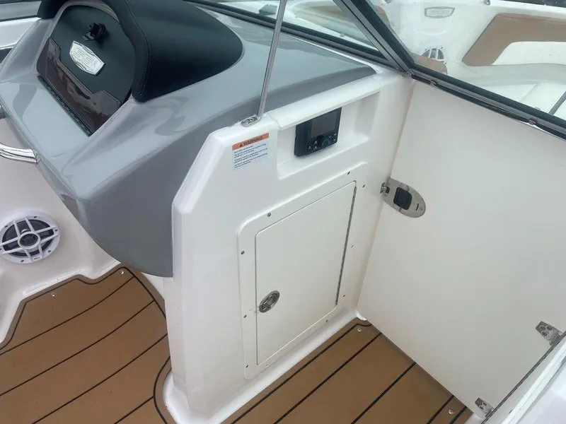 Slide: The Image of 2023 Chaparral 21 SSi boat interior with sleek dashboard and wood-style flooring. - 7