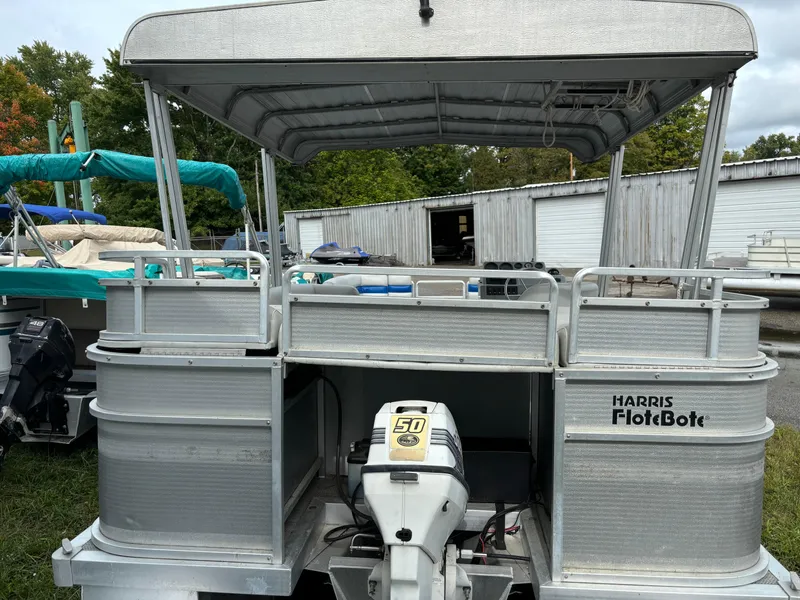 Slide: The Image of 1992 Harris FloteBote 240 Classic pontoon boat with outboard motor, docked outdoors. - 4