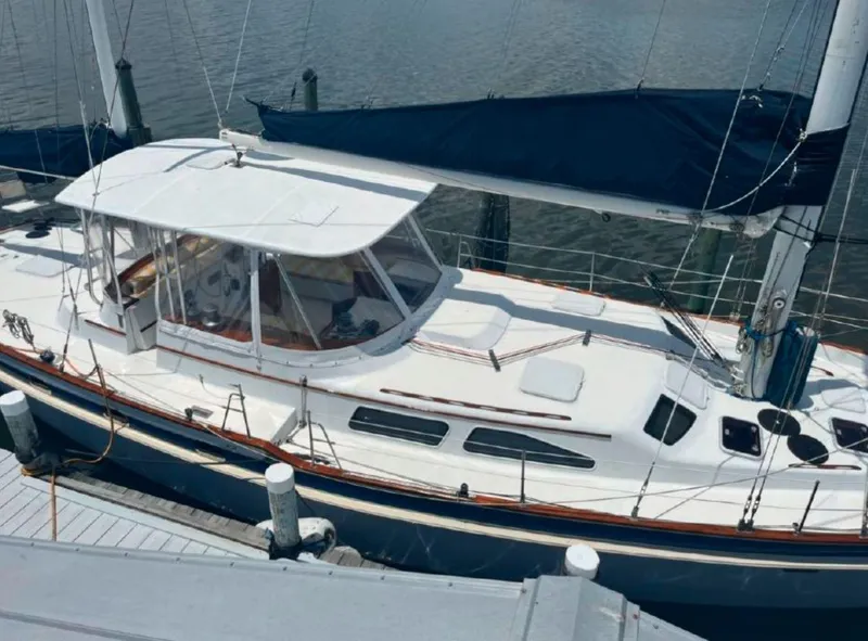 Slide: The Image of 1990 Irwin 54 sailboat docked, featuring a sleek white design and blue sail cover. - 12