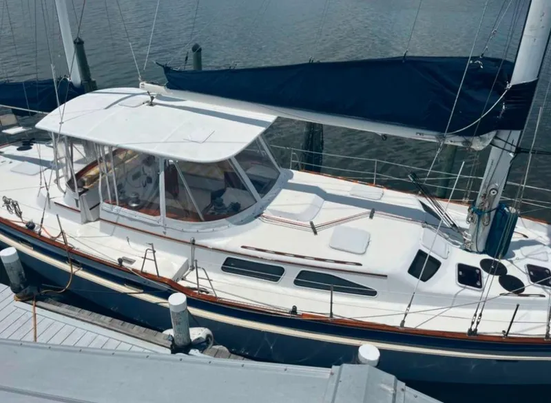 Slide: The Image of 1990 Irwin 54 sailboat docked, featuring a sleek white design and blue sail cover. - 4