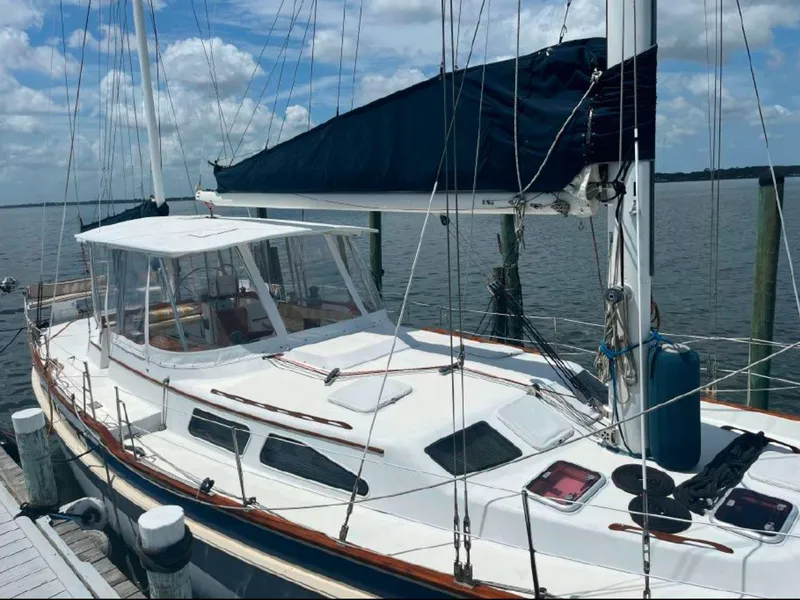 Slide: The Image of 1990 Irwin 54 sailboat docked, featuring a sleek white deck and blue sail cover. - 8