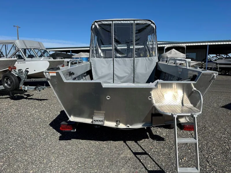 Slide: The Image of 2025 Hewescraft 200 Sportsman boat, rear view, parked outdoors under clear blue sky. - 3