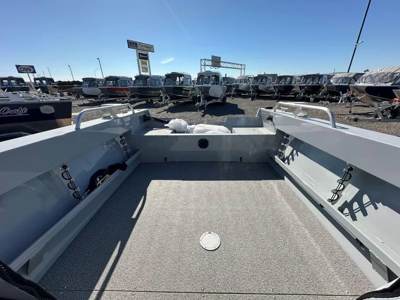 Slide: The Image of 2025 Hewescraft 200 Sportsman boat interior at dealership, showcasing spacious deck and seating. - 7