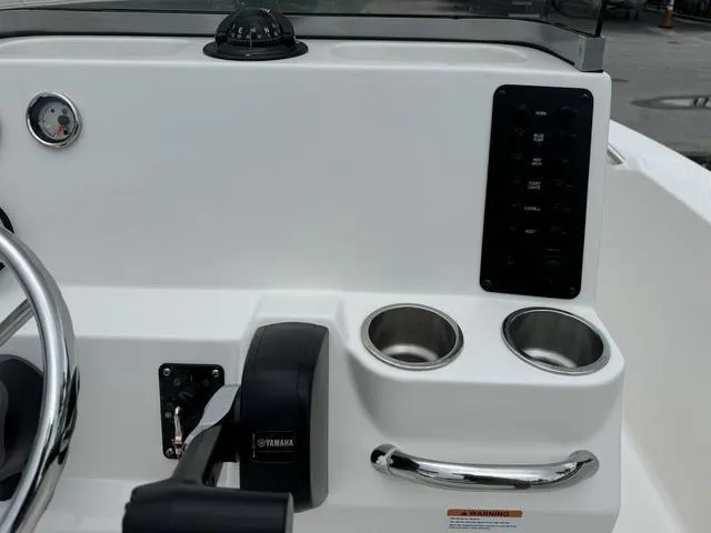 Slide: The Image of 2025 Robalo R160CC boat console with steering wheel, compass, and cup holders. - 18