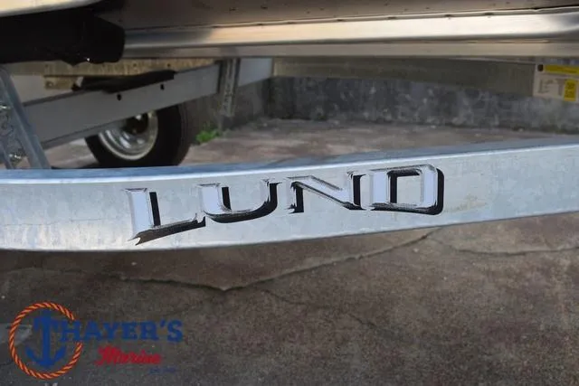 Slide: The Image of 2025 Lund SSV-16 Tiller boat trailer with logo, parked on concrete. - 7