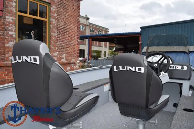 Slide: The Image of 2025 Lund 1600 Fury SS boat interior with branded seats, parked near brick building. - 12