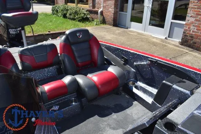 Slide: The Image of 2015 Triton 189 TRX boat interior with red and black seats, parked outdoors. - 22