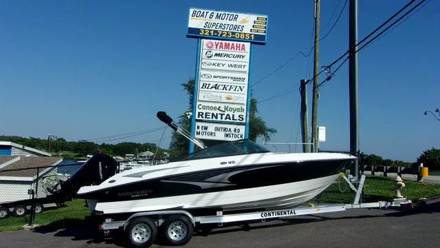 Slide: The Image of 2023 Monterey M-225 boat on trailer at dealership with rental services sign. - 1