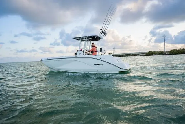 Slide: The Image of 2025 Yamaha Boats 220 FSH Sport cruising on open water under cloudy sky. - 3