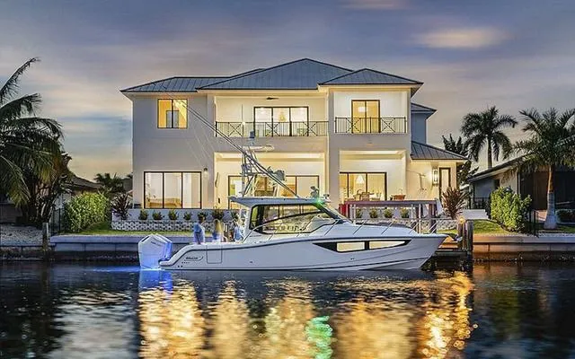 Slide: The Image of 2025 Boston Whaler 365 Conquest boat docked by a luxurious waterfront home at sunset. - 1