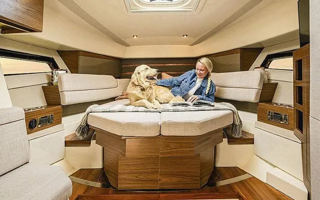 Slide: The Image of 2025 Boston Whaler 365 Conquest cabin interior with woman and dog relaxing. - 4