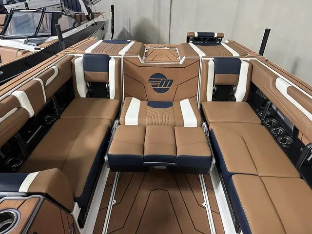 Slide: The Image of 2025 Malibu 25 LSV boat interior with luxurious tan and navy seating. - 20
