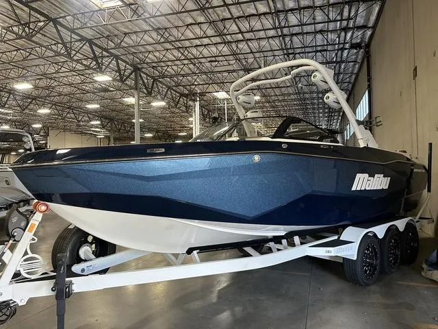 Slide: The Image of 2025 Malibu 25 LSV boat in warehouse, blue exterior, on trailer. - 4