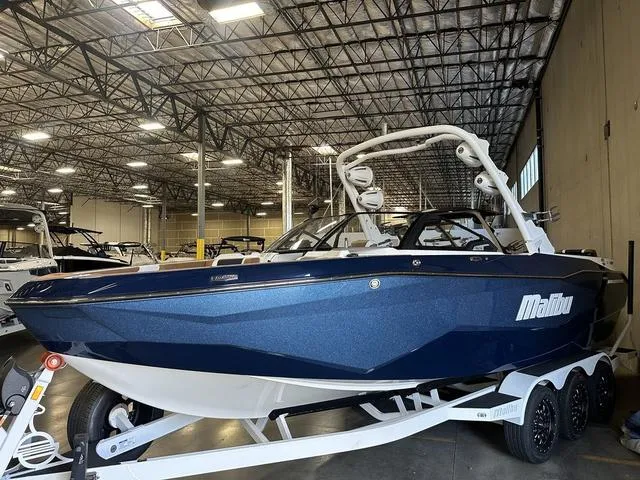 Slide: The Image of 2025 Malibu 25 LSV boat in warehouse, blue exterior, on trailer. - 5