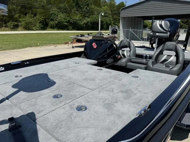 Slide: The Image of 2025 Bass Cat Cougar FTD boat with spacious deck and seating, parked outdoors. - 13