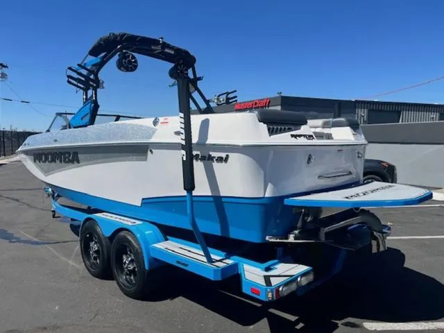 Slide: The Image of 2021 Moomba Makai boat on trailer, blue and white design, parked outdoors. - 8